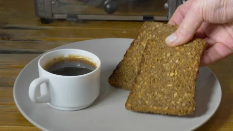 Placing rye bread slices from a toaster on a plate next to a cup of coffee. Stock Footage 142273544