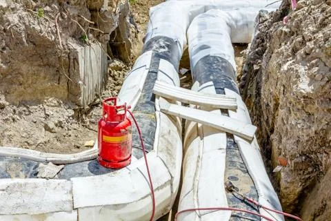Placing set of Styrofoam thermal insulation on new pipeline in trench Stock Photos