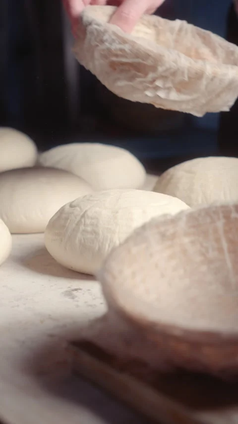 Placing shaped bread dough pieces onto a baking board before baking Stock Footage 344313304