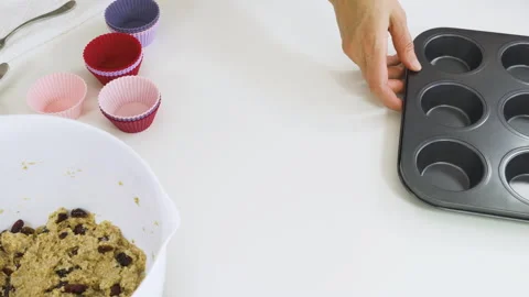 Placing silicon muffin cups on a baking sheet. Bran muffins with dry cranberries Stock Footage 136723297