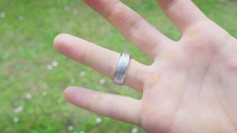 Placing Silver Ring On Ring Finger White Male Hand On Grass Backdrop Stock Footage 311123145