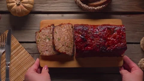 Placing Sliced Meatloaf Board on Rustic Wooden Table Top View Stock Footage 328094480