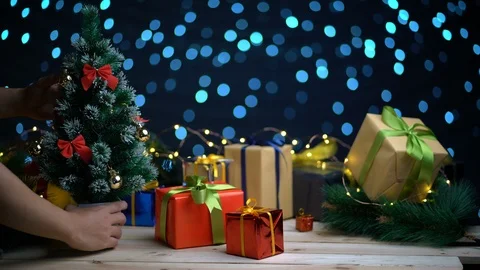 Placing Small Christmas Tree Between Christmas Presents Against Beautifull Bl Stock Footage 96152292