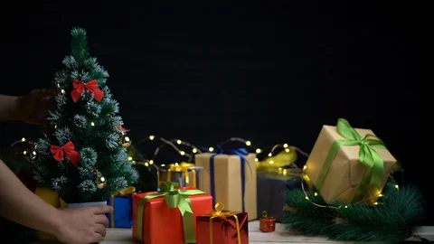 Placing Small Christmas Tree Between Christmas Presents Against Dark Backgrou Stock Footage 96152307