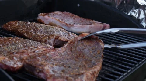 Placing steak on BBQ grill with tongs - Barbecue Stock Footage 68655853
