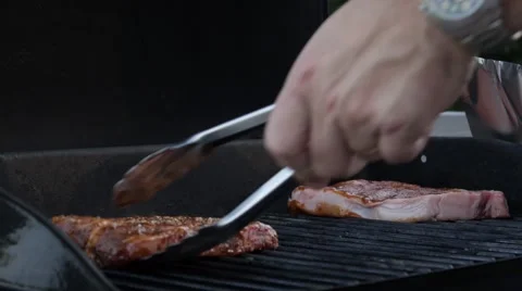 Placing steaks on  grill with tongs Stock Footage 68655867