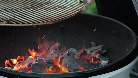 Placing a steel grate over burning charcoal on an outdoor barbecue grill Stock Footage 340164238