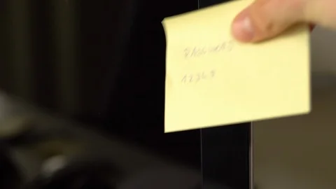 Placing sticky note with weak password on to computer as a reminder. Stock Footage 92882546