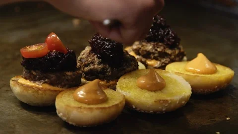Placing tomatoes onto burger with meatballs, beetroot relish and sauce Stock Footage 91371644
