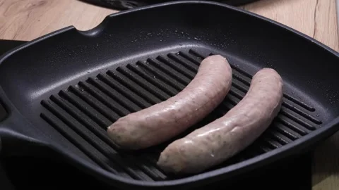 Placing Two Fresh Sausages on a Black Grill Pan. Stock Footage 253903299