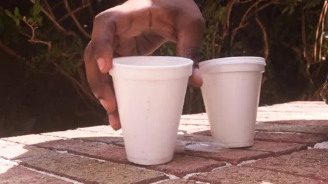Placing a White Disposable Cup on a Brick Park Wall Stock-Footage 347586835