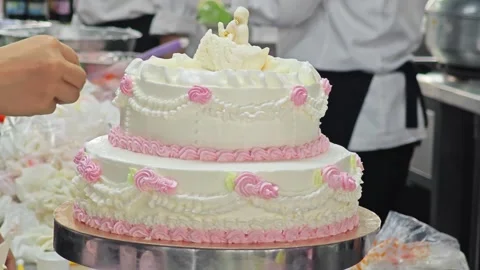 Placing a white swan topper onto a two-tiered vintage wedding cake. Stock Footage 344746748