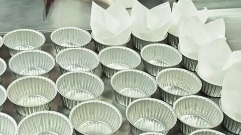 Placing white tulip paper liners into aluminium cups on a tray. Stock Footage 346709773