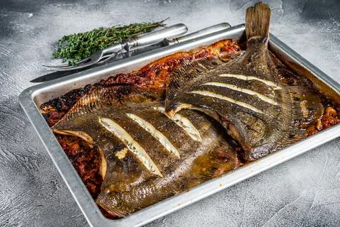 Plaice or Flounder flat fish baked in a tomato sauce in baking tray. White Stock Photos