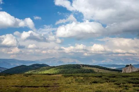 Plain. In the background, the mountains are surrounded by a blue sky and clouds. Stock Photos