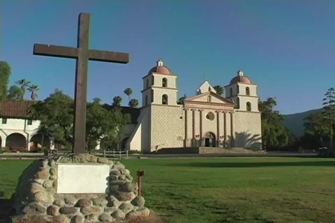 A plain cross embedded in stone occupies the lawn in front of a Catholic mission Stock Footage