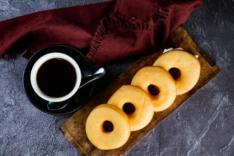 Plain Donuts with cup of black coffee served on wooden board isolated on na.. Stock Photos