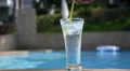 Plain Glass of Water with Ice Cubes near Blue Swimming Pool HD Footage