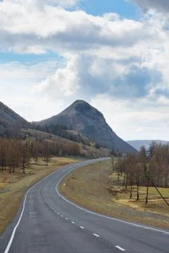 Plain with highway at root of mountains Stock Photos