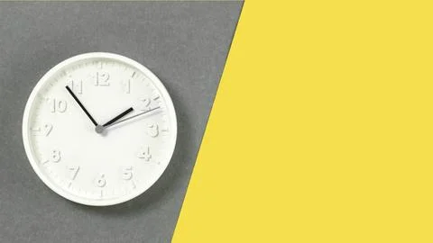 Plain wall clock in the center on grey amd yellow banner Stock Photos