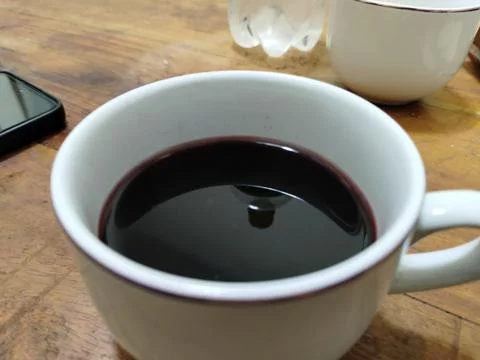 A plain white ceramic cup filled with dark red wine Stock Photos