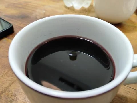 A plain white ceramic cup filled with dark red wine Stock Photos