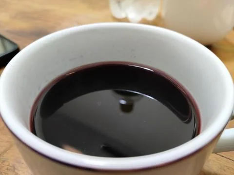 A plain white ceramic cup filled with dark red wine Stock Photos