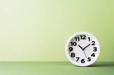 Plain white clock on pastel warm green banner Stock Photos