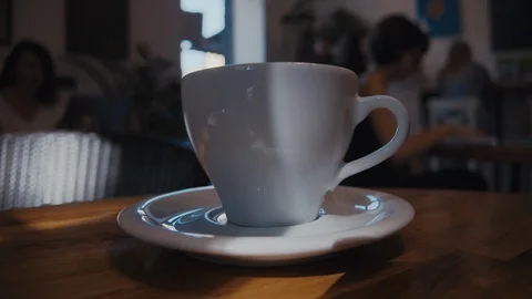 Plain white coffee cup on table in the cafeteria, defocus people at background 스톡 동영상 115513379