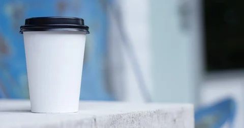 Plain white to go coffee cup on table outdoors - copy space right Video stock 94648058