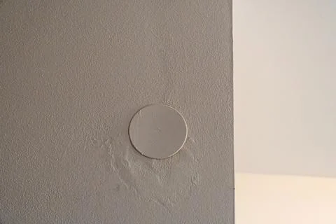 A plain white wall with a circular patch, showcasing a minimalist interior 스톡 사진