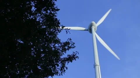 Plain wind weel beside a tree in front of a blue sky 스톡 동영상 11703484