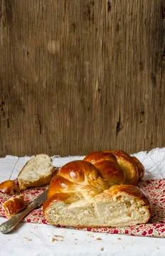 A plaited loaf of bread on a floral-patterned cloth against a wooden ball 写真素材