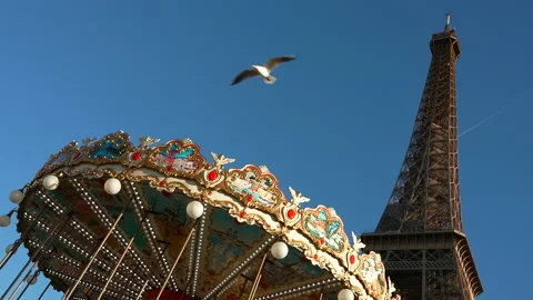 A plane and bird fly over a romantic merry-go-round at the Eiffel Tower in Stock Footage 170000417