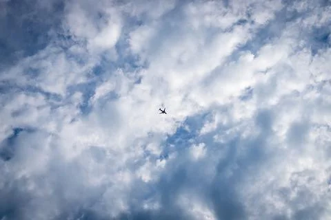 The plane on a background of the blue sky with clouds. Plane silhouette in th Stock Photos