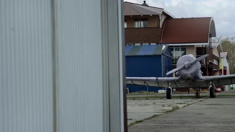 The plane is in a cover against the background of house and a hangar Vidéo 153665527