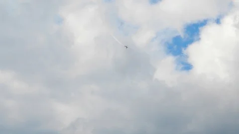 A plane is doing aerobatics high in a grey cloudy sky. Stock Footage 121252406