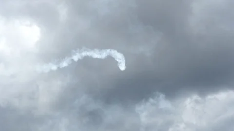 A plane is doing aerobatics high in a grey cloudy sky. Stock Footage 121252439