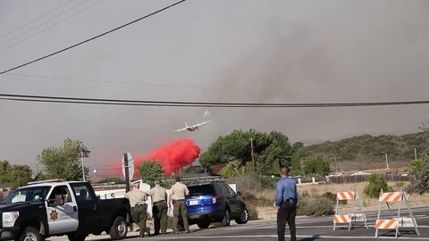 Plane drops red fire retardant, cops in foreground Stock Footage 114413365