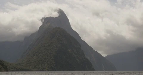A plane is dwarfed by the massive mountains of Milford Sound, New Zealand Stock Footage 120491664