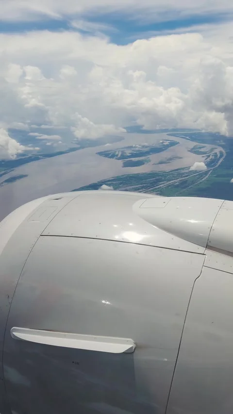 Plane engine looking out of window of an airplane flying over the Amazon River 스톡 동영상 309121787