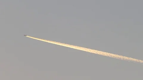 Plane in the evening sky with golden contrails Stock Footage 106675868