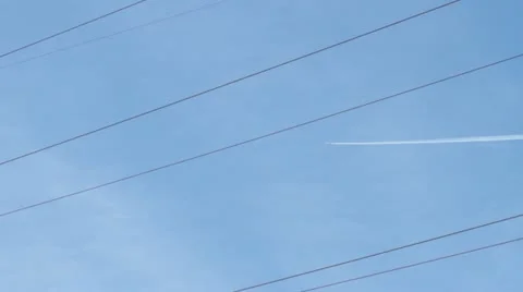 A plane flies high above through power lines Stock Footage 21885268
