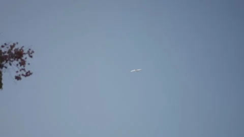A plane flies high in a clear blue sky Stock Footage 226757213