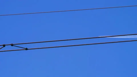 The plane flies, leaves a trace in the sky against the background of wires Video stock 140106862