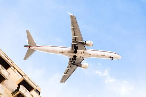 A plane flies over a building Stock Photos