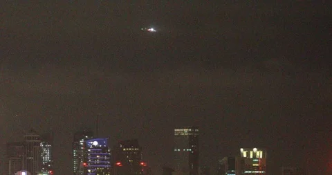 Plane flies over buildings in Doha by night Stock Footage 122652359