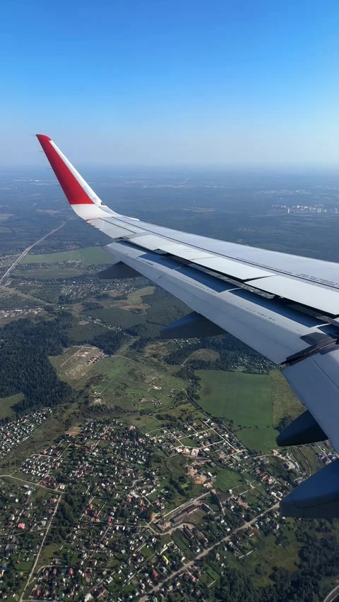 The plane flies over the city, preparing to land on the runway, window view Stock Footage 305601556