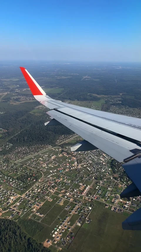 The plane flies over the city, preparing to land on the runway, window view Stock Footage 305601706