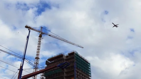 Plane flies over construction of a high-rise office building. Stock Footage 97444717